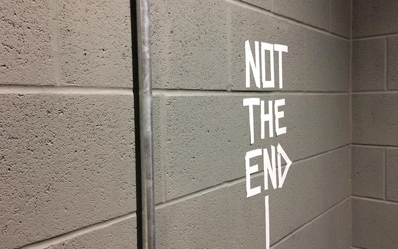 It's Not The End taped in white on a grey wall